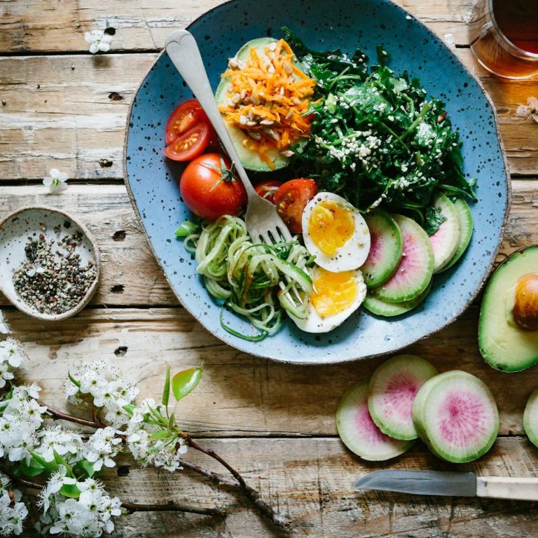 Angebot: Das perfekte Frühstück Bunt dekorierter Teller mit Gemüse, Eiern und Avocado auf einem Holztisch.