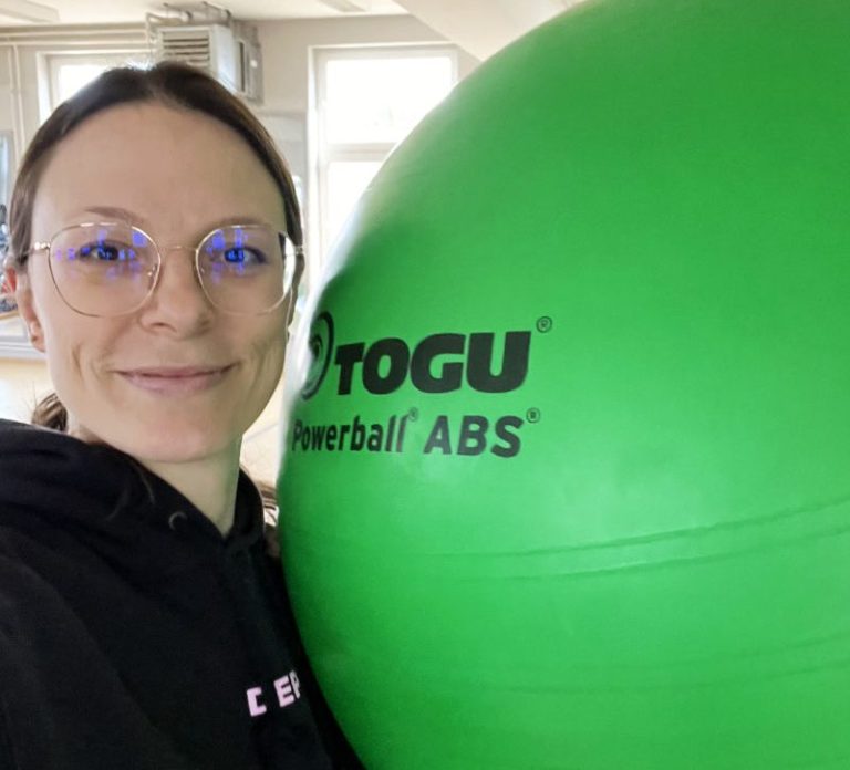 Fitnesstraining und Seniorengymnastik in Hamburg Frau mit Brille hält einen großen grünen Gymnastikball in der Hand.